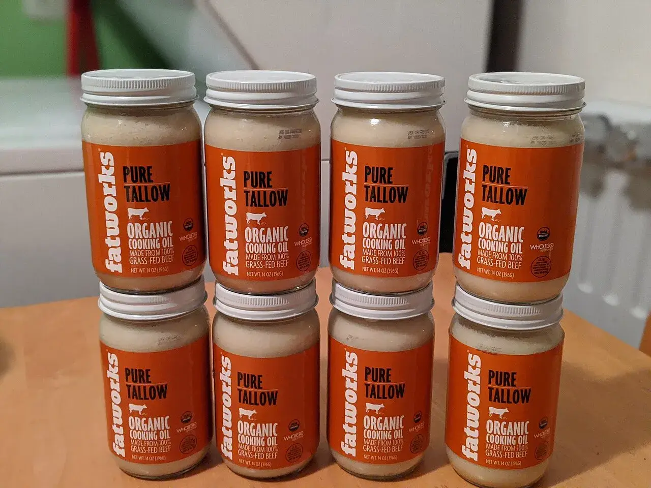 Retail jars of pure beef tallow stacked on a table, labels facing the camera