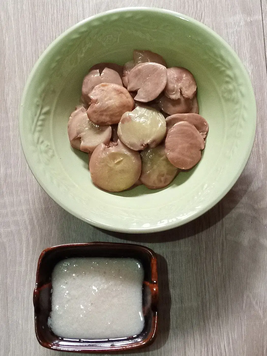 Solid white coconut oil in a dish beside pieces of coconut flesh