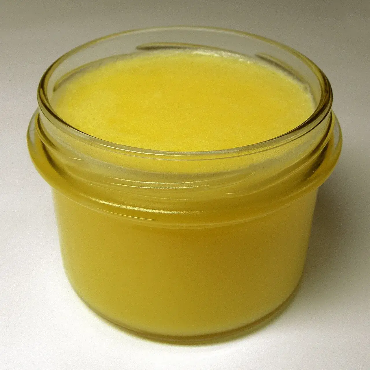 A glass jar of clarified butterfat, deep yellow and set