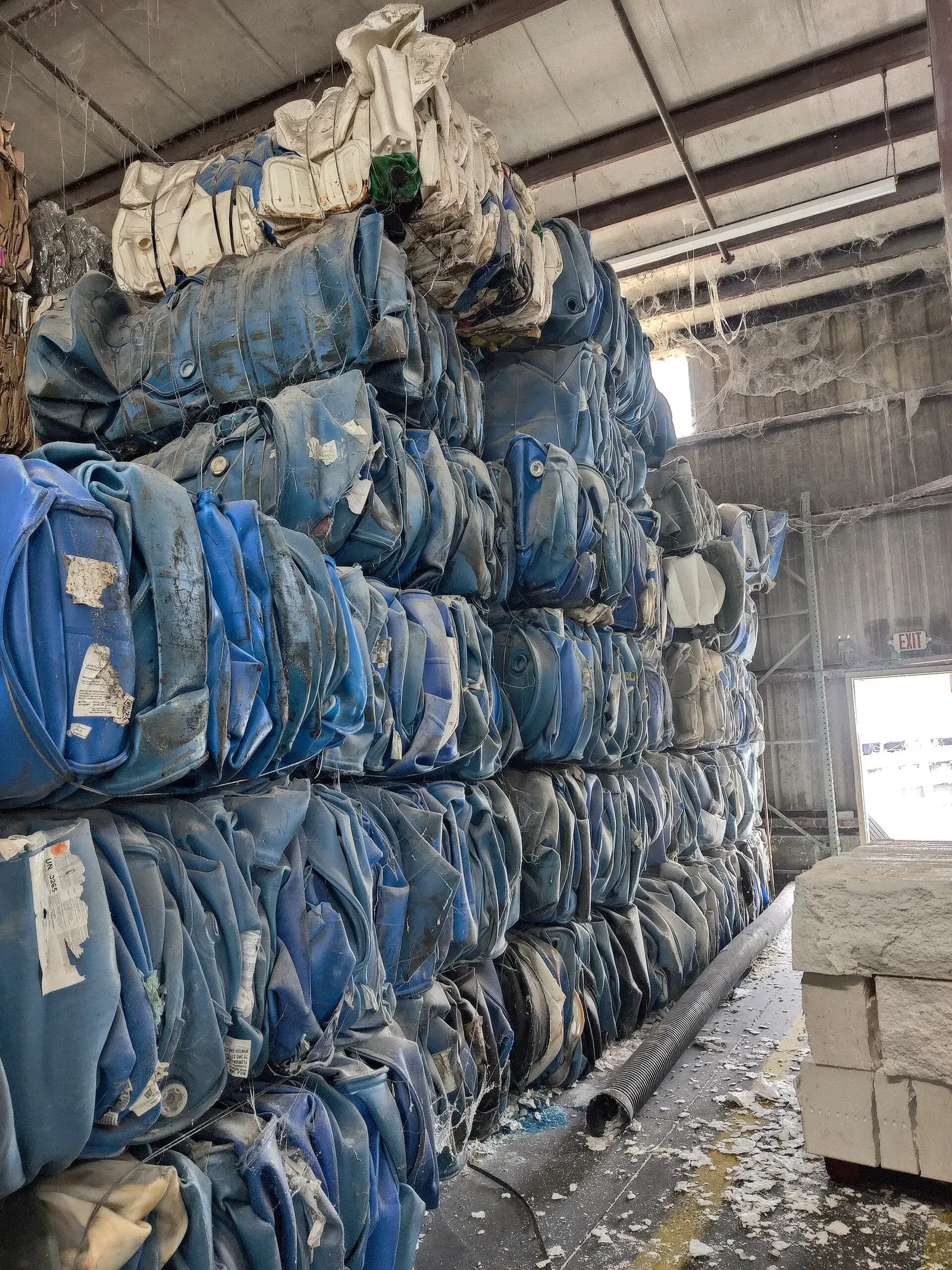 Stacked bales of blue HDPE 55-gallon plastic drums