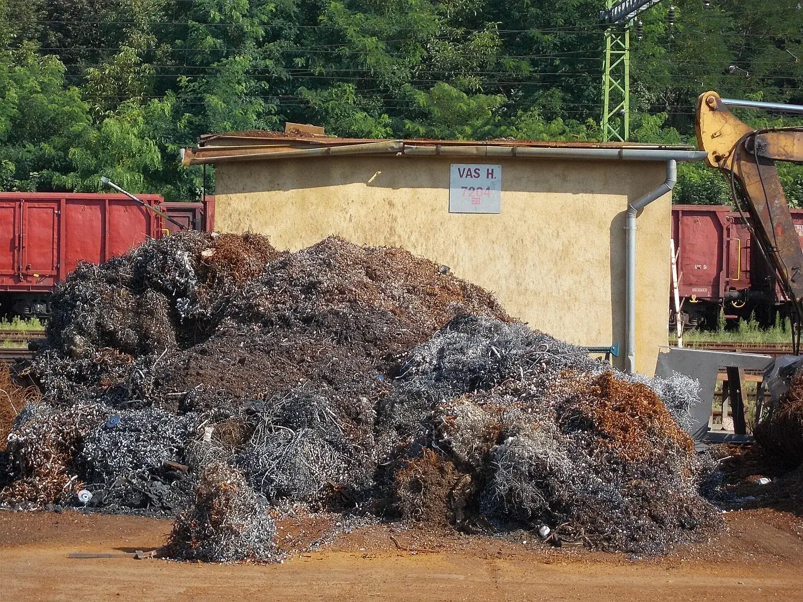 Pile of mixed ferrous scrap beside rail wagons
