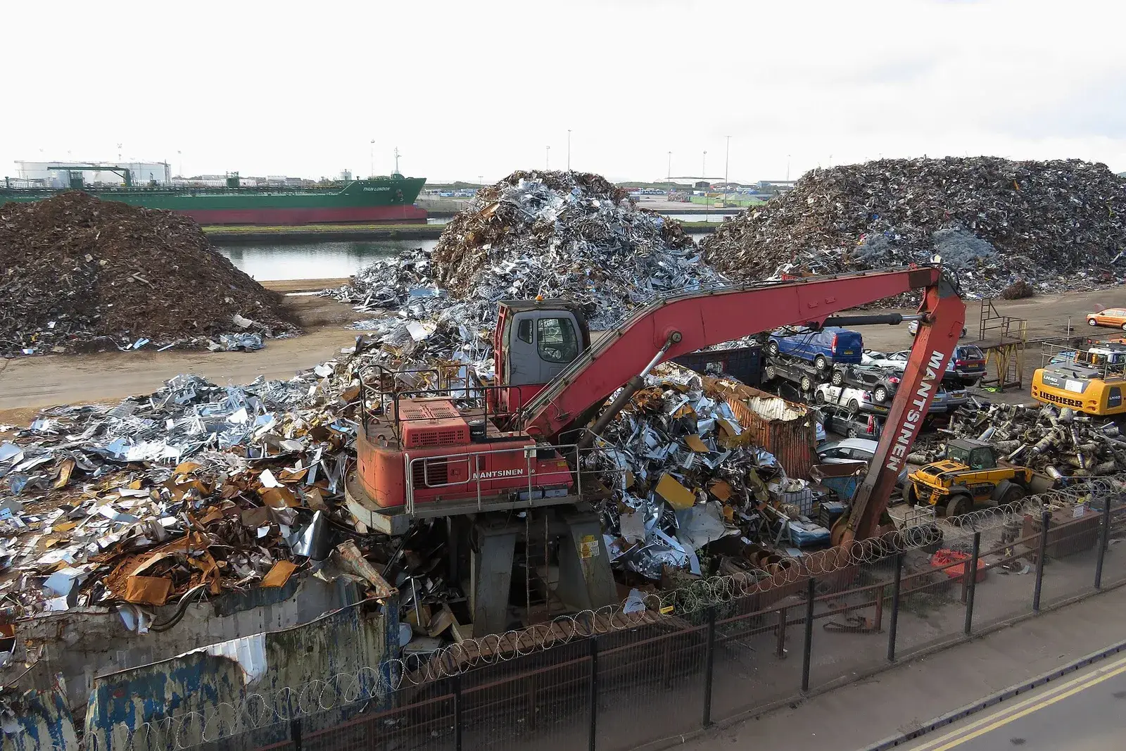 Material handler working a large ferrous scrap stockpile at a port