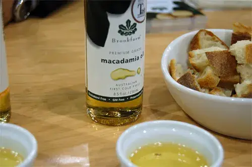 A bottle of premium cold-pressed macadamia oil beside dishes of the oil and bread