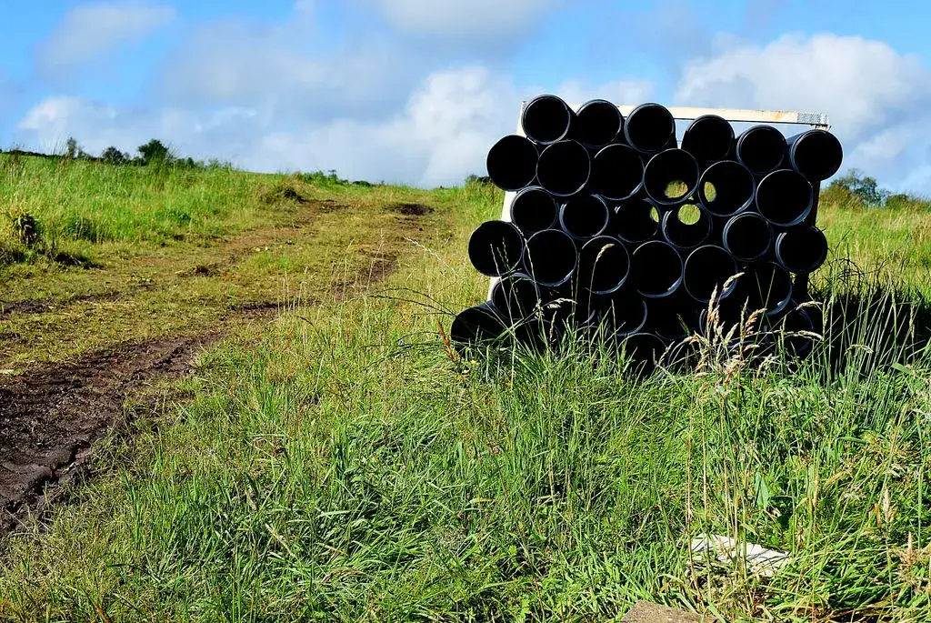 Stack of black PVC pipes in a field