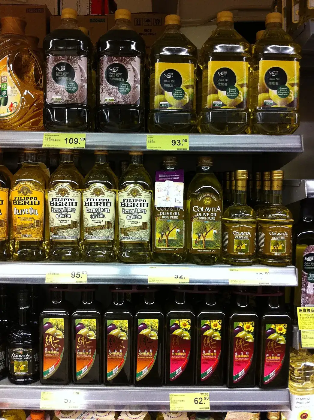Glass bottles of olive oil in different grades on a supermarket shelf