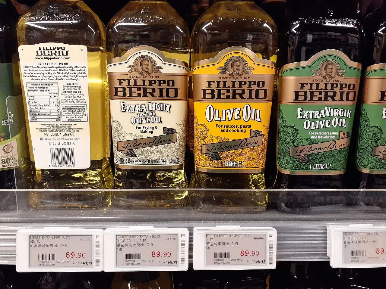 Bottles of extra light, refined and extra virgin olive oil side by side on a shop shelf