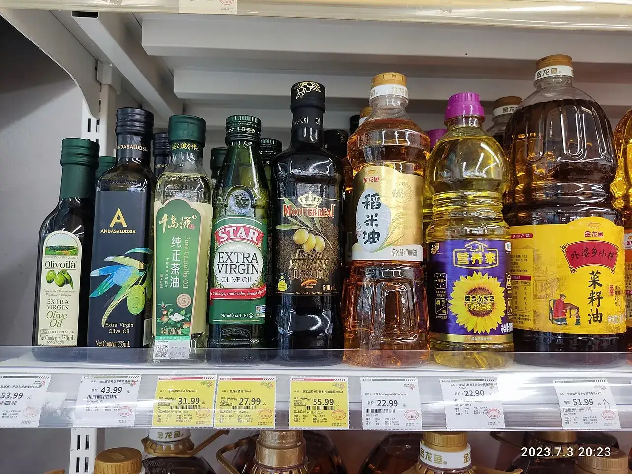 Supermarket shelf of bottled cooking oils in a range of pack sizes