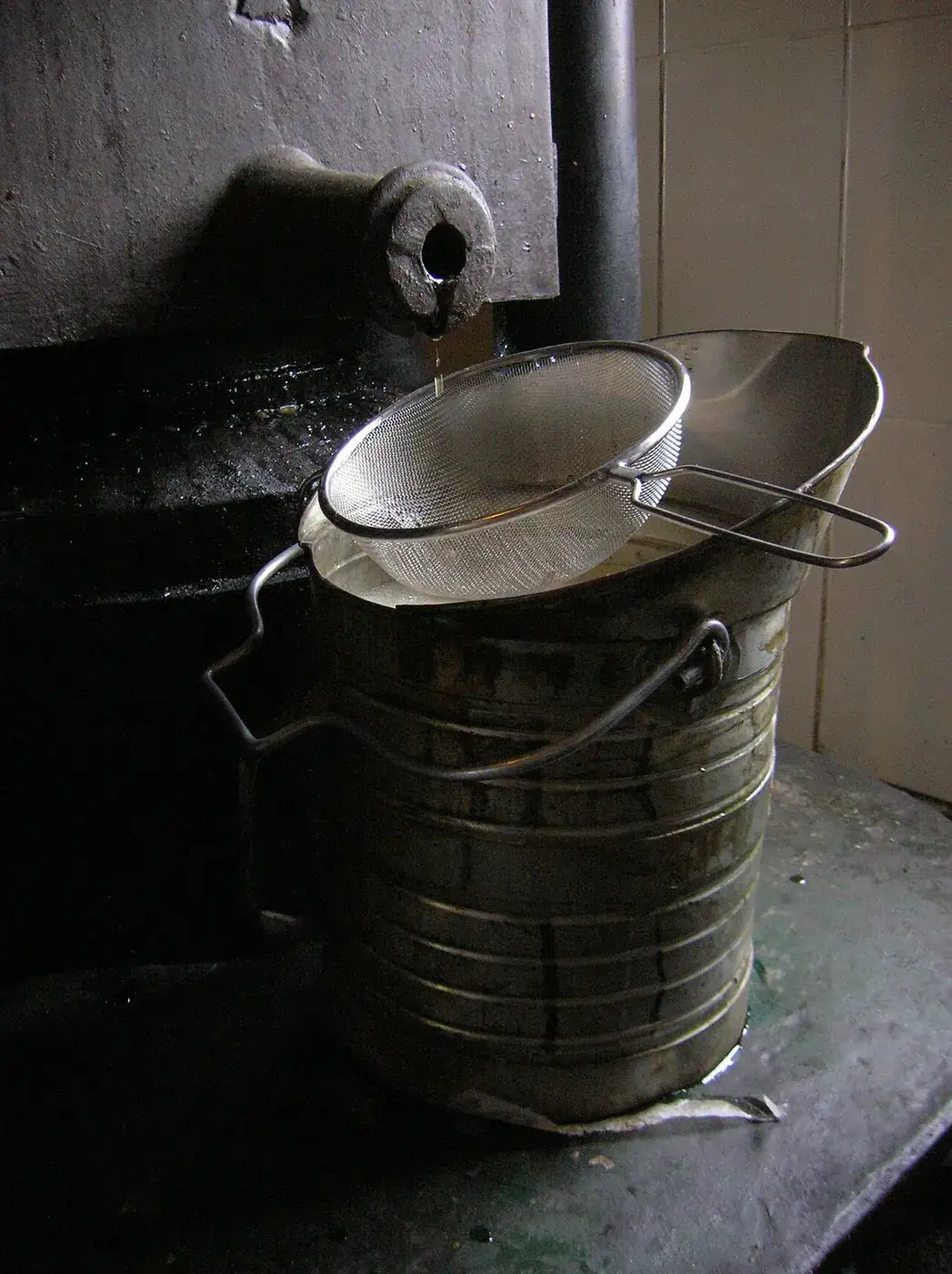 Walnut oil running into a pail at a traditional oil mill