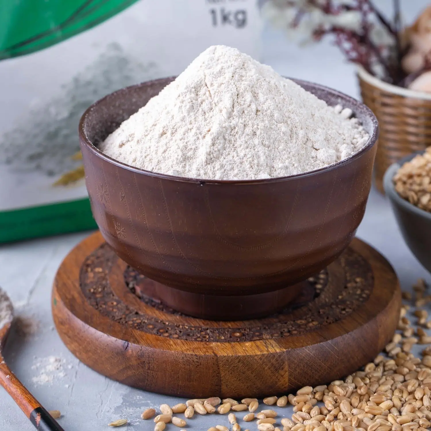 Wooden bowl of white wheat flour beside a 1 kg flour bag